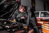A mechanic working on a car engine in a garage. Voir les images du produit