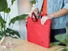 A person is placing a red wireless mouse into a red laptop bag. Anteprima dell’immagine prodotto