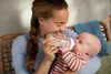 A woman is feeding a baby with a bottle. Produktbild-Vorschau