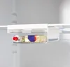 A close-up shot of a transparent refrigerator drawer with a tube of toothpaste and a stick of butter inside, attached to a refrigerator shelf. Produktbild-Vorschau