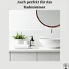 A clean, modern bathroom vanity with a sink, soap dispenser, plant, and folded towels, with a round mirror above. Produktbild-Vorschau