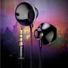 Close-up of black earphones with a gold audio jack, set against a blurred background of a concert crowd. Podgląd zdjęcia produktu