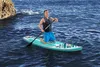 A man kneeling on a paddleboard in the ocean, holding a paddle. Produktbild-Vorschau
