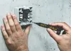 A person is using a black and yellow electrical tester to check an electrical outlet. Produktbild-Vorschau