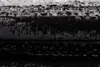 A close-up view of a textured rug with horizontal stripes in black, gray, and white. Produktbild-Vorschau