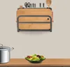 A kitchen utensil holder with cutting boards and kitchenware displayed on a wall, with a pot and salad on a counter below. Voir les images du produit