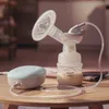 A breast pump and its accessories are placed on a wooden table. Produktbild-Vorschau
