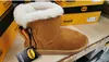 A single brown winter boot with white fur trim and a yellow bow, displayed on a shelf with product boxes in the background. Produktbild-Vorschau