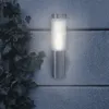 A modern outdoor wall lamp mounted on a textured wall, with ivy growing on the left side. Produktbild-Vorschau