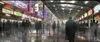 A bustling futuristic train station or marketplace with many people and bright, colorful advertisements. Produktbild-Vorschau