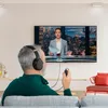A man wearing headphones is watching TV, holding a remote control. Produktbild-Vorschau