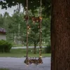 A rope swing decorated with fairy lights hangs from a tree. Podgląd zdjęcia produktu