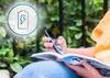 A person is sitting outdoors, reading a book and using a scanning pen. A battery icon is overlaid on the image. Náhľad obrázku produktu