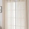 A close-up view of sheer beige curtains hanging in front of a window. Produktbild-Vorschau