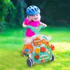A young child wearing a helmet is playing with a multi-functional baby walker in a grassy outdoor setting. Podgląd zdjęcia produktu