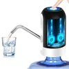 A water bottle pump is shown dispensing water into a glass. The pump has a black and white body with blue illuminated internal components. A finger is pressing the button on top of the pump. Produktbild-Vorschau
