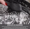 A hand is cleaning a grill with a sponge and soap. Produktbild-Vorschau