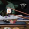 Chopsticks holding a sushi roll with other sushi dishes in the background. Produktbild-Vorschau