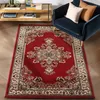 A red oriental rug with a traditional medallion pattern is placed on a wooden floor in front of a blue armchair with two pillows. Produktbild-Vorschau