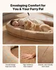 A woman and a golden retriever dog are lying together on a large, oval-shaped pet bed. Produktbild-Vorschau