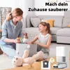 A mother and daughter are playing with toys in a living room, with a robot vacuum cleaner and its accessories in the foreground. Produktbild-Vorschau