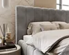 A close-up view of a bed with a gray velvet headboard and beige bedding. Náhled obrázku produktu