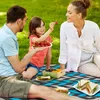 A family is having a picnic on a blanket in a grassy area. Náhľad obrázku produktu