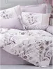 A neatly made bed with lilac bedding and pillows featuring a floral leaf pattern. Produktbild-Vorschau