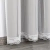 Close-up of white lace-trimmed curtains hanging near a floor. Anteprima dell’immagine prodotto