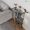 A drying rack with clothes is placed next to a sofa in a room. Produktbild-Vorschau