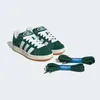 A pair of green Adidas Campus 00s sneakers with white laces and white Adidas stripes, shown with two extra pairs of green laces. Podgląd zdjęcia produktu