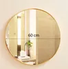 A round mirror with a golden frame is shown on a wall, reflecting a bathroom interior. A measurement line indicates the diameter is 60 cm. Náhľad obrázku produktu