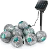 A string of solar-powered decorative lights with eight spherical lanterns, each featuring a perforated silver metal design with a blue interior, connected to a solar panel on a stake. Produktbild-Vorschau