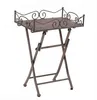 A metal folding side table with a woven top and decorative scrollwork on the edges. Produktbild-Vorschau