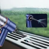 A blue handheld vacuum cleaner is shown cleaning a car vent. A close-up inset shows the nozzle of the vacuum cleaner emitting a stream of air. Náhled obrázku produktu