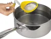 A hand is holding a yellow egg poacher over a pot of water. Náhled obrázku produktu