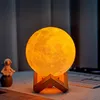 A moon-shaped lamp with a wooden stand is placed on a surface, with a small astronaut figurine to the left. Podgląd zdjęcia produktu