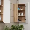 A bathroom cabinet with its door open, showing shelves with various toiletries and bottles. A plant is visible in the foreground. Podgląd zdjęcia produktu
