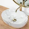A marble-patterned sink with a gold faucet on a wooden surface. Náhled obrázku produktu