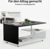 A modern black and white coffee table with two shelves, shown in a clean, minimalist setting. A glass of water and some books are placed on the table and shelves. Produktbild-Vorschau