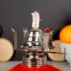 Close-up of the top of a red oil lamp with a silver wick holder and wick. Náhled obrázku produktu