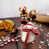 Christmas-themed treats, likely marshmallows dipped in chocolate and decorated to look like reindeer, are arranged on a wooden surface with scattered sprinkles and pretzels. Náhled obrázku produktu