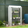 A small greenhouse with plants inside, placed on a patio next to a fence and a water barrel. Produktbild-Vorschau