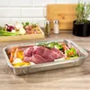 A raw piece of meat and vegetables are arranged in a roasting pan on a wooden surface. Náhled obrázku produktu
