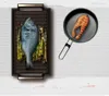 A cooking surface with a whole fish and asparagus on one side, and a salmon fillet in a pan on the other. Náhled obrázku produktu