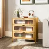 A wooden dresser with three drawers, each with a ribbed glass front, is placed in a room next to a sofa. A vase of flowers and a book are on top of the dresser. Podgląd zdjęcia produktu