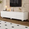 A white TV stand with scalloped edges and round legs is shown in a living room setting. Produktbild-Vorschau