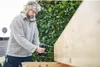 A man is using a cordless drill to screw into a wooden beam outdoors. Voir les images du produit
