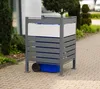 A metal trash can enclosure with a blue bin inside, placed on a paved walkway next to greenery. Náhled obrázku produktu