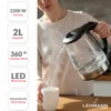 A person is pouring hot water from a glass kettle into a white mug. Steam is rising from the mug. Produktbild-Vorschau